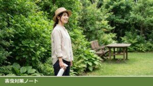夏の庭で、帽子をかぶった女性が白いスプレーボトルを体の横に下げて立ち、後ろに木のテーブルと椅子が見える様子