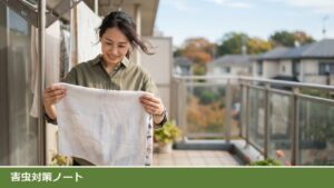 秋の晴れたベランダで、女性が取り込む前のバスタオルを両手で広げ、裏側を目で見て確かめている様子